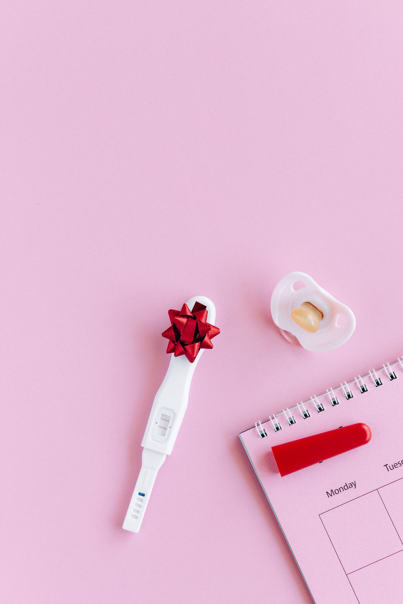 Pregnancy test, calendar and pacifier arranged for pregnancy planning